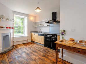 Eine Küche mit Holzboden, einem Herd und einem Fenster.