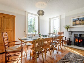 A dining area with wooden furniture, a fireplace, and large windows.