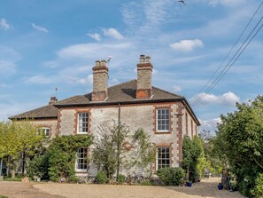 A two-story stone building with a traditional design, featuring a chimney, multiple windows, and a sign indicating guest parking.