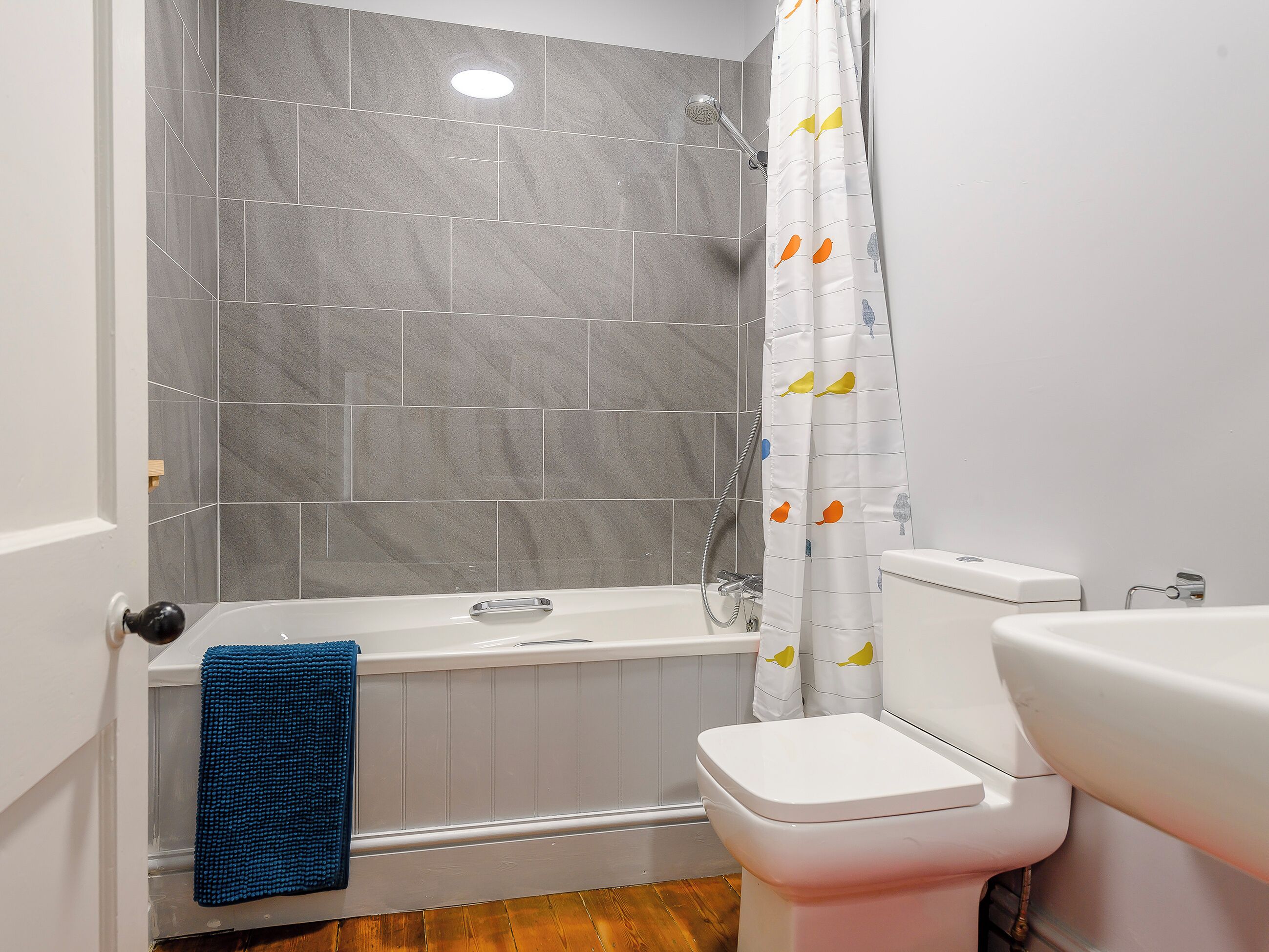 A bathroom with a bathtub, toilet, and shower area.