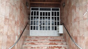 Un escalier en marbre avec des rampes métalliques menant à une porte blanche dotée de panneaux de verre.