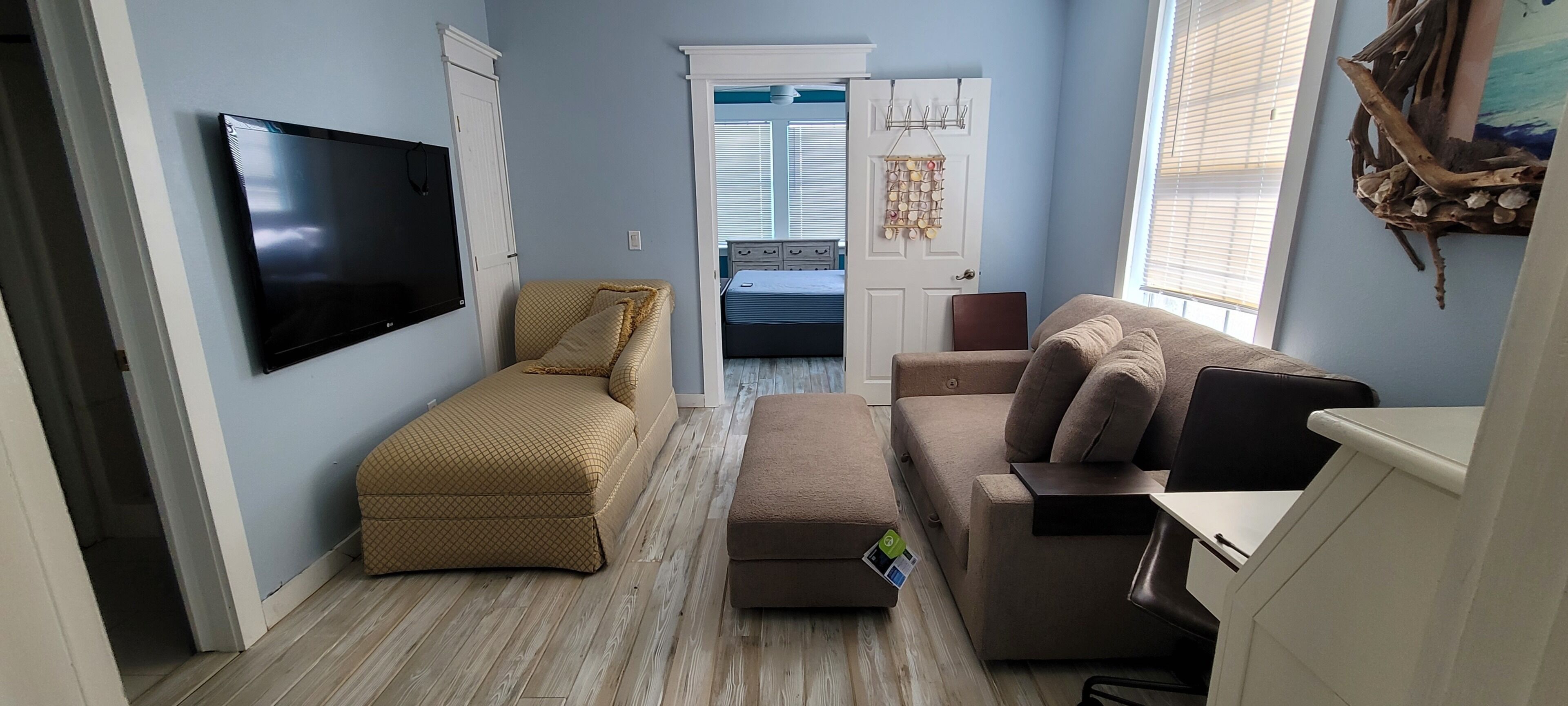 A compact living space with a flat-screen TV, a sofa, a loveseat, and a small table.