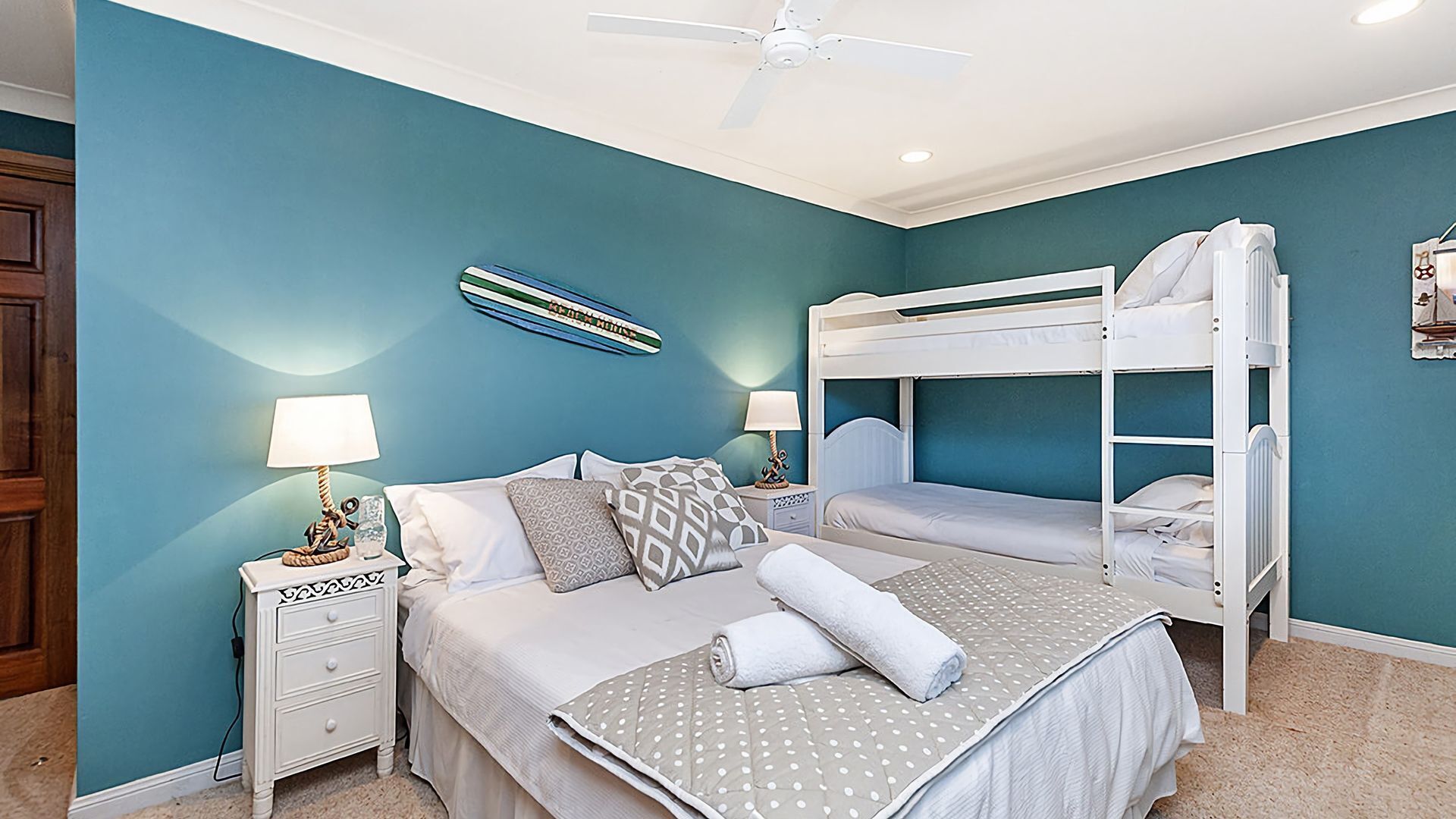 A bedroom with a bunk bed, a single bed, and a nightstand with lamps.