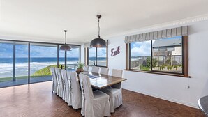 A dining area with a view of the ocean, a large window with a 'Eat' sign, and a modern interior design.