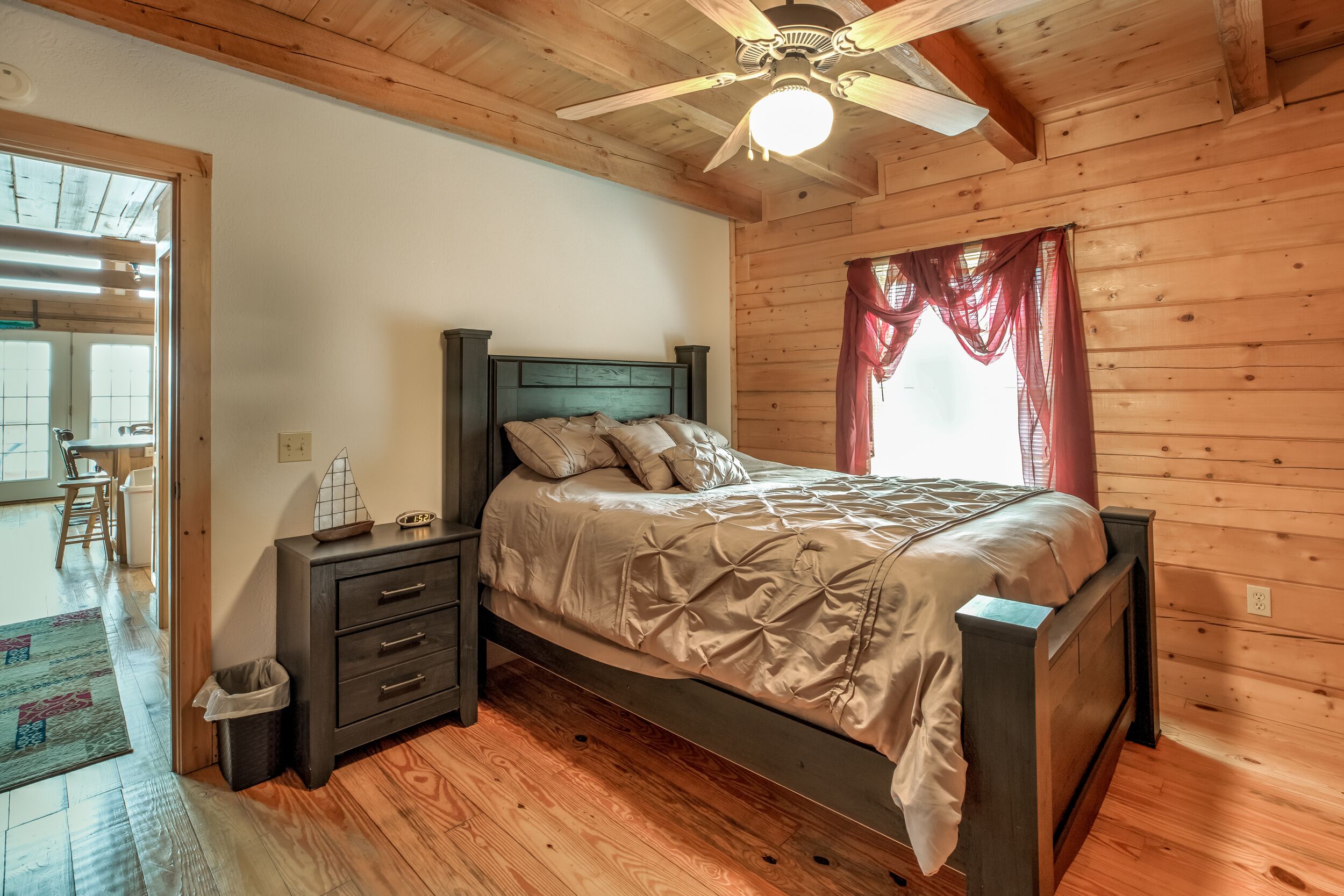 Un dormitorio con paneles de madera, una cama, mesitas de noche y un ventilador de techo.
