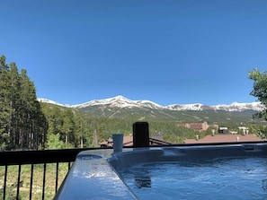A hot tub with a mountain view, surrounded by trees and buildings.