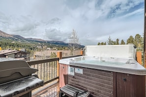 A hot tub on a deck with a mountain view.