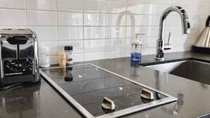 Una cocina moderna con una placa de inducción empotrada, un tostador y un grifo de acero inoxidable.