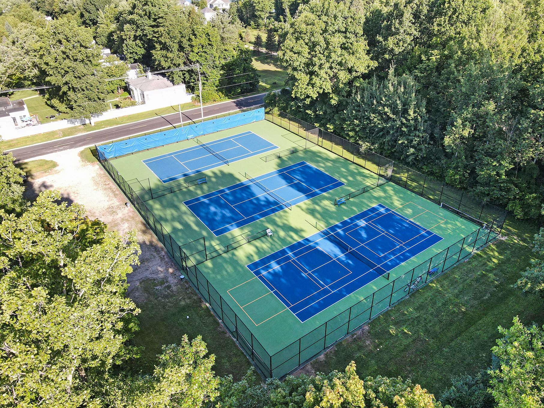 Una cancha de tenis al aire libre rodeada de árboles.