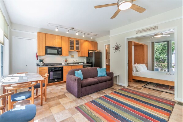 Un espacio habitable compacto con kitchenette, sofá, zona de comedor y cama.