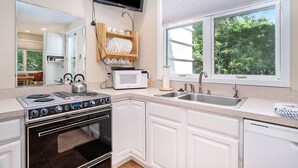 A modern kitchen with white cabinets, a built-in oven, a microwave, and a sink. - Sleepy Hollow Beach Resort, Cottage 3D – Family Fun on Lake Michigan! (South Haven)