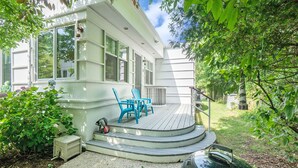 A house with a wooden deck, a barbecue grill, and two blue chairs. - Sleepy Hollow Beach Resort, Cottage 3D – Family Fun on Lake Michigan! (South Haven)