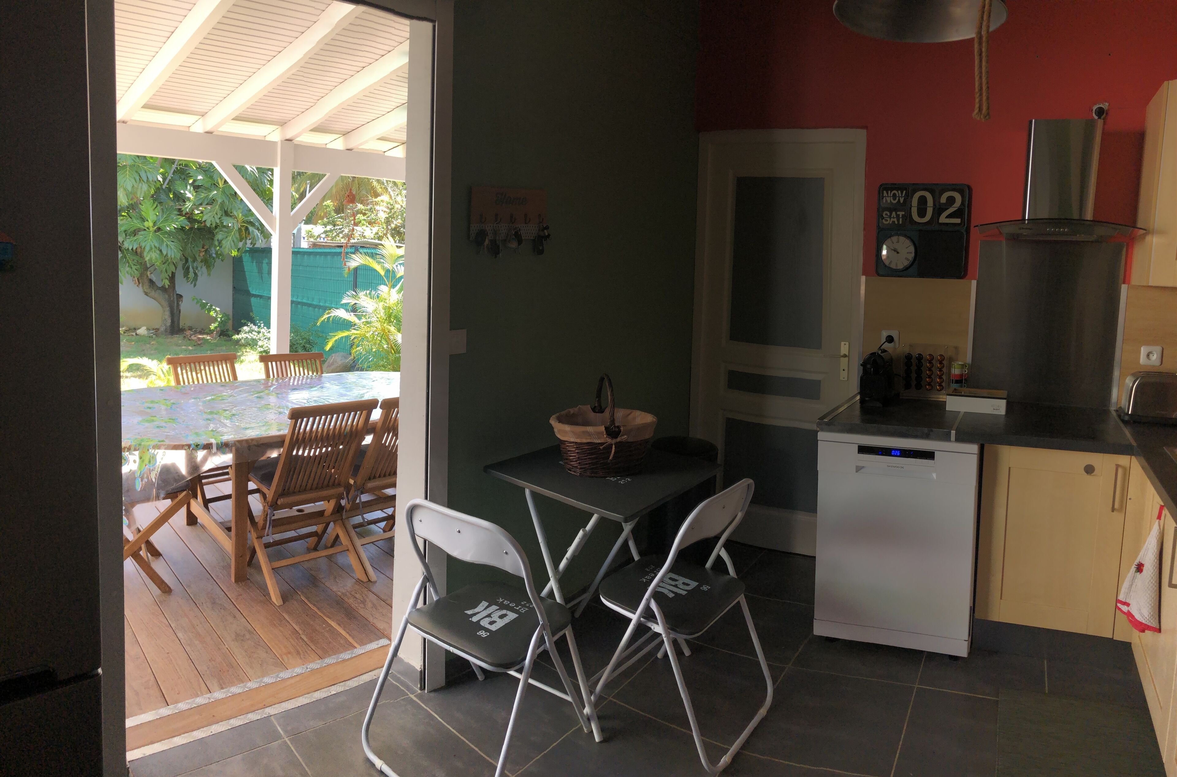 A compact kitchen with a dining area, a small refrigerator, and a clock on the wall.