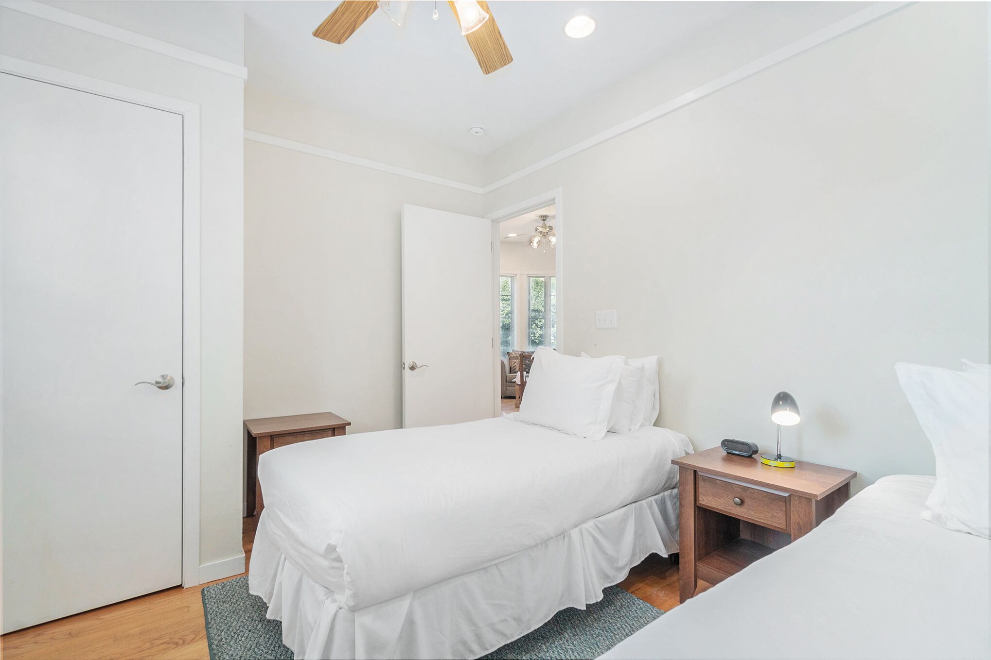 A bedroom with a bed, a bedside table with a lamp, and a door.