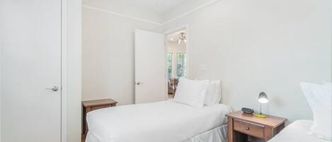 A bedroom with a bed, a bedside table with a lamp, and a door.