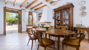 A dining area with a wooden table and chairs, a cabinet with glass doors, and a view of the outside. - CAN MORA - Villa with private pool in Campos. Free WiFi (Campos)
