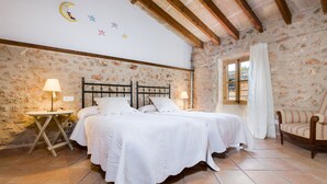 A bedroom with two beds, a nightstand, a chair, and a window with curtains. - CAN MORA - Villa with private pool in Campos. Free WiFi (Campos)
