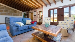 A cozy living room with a blue sofa, wooden coffee table, and patterned armchairs. - CAN MORA - Villa with private pool in Campos. Free WiFi (Campos)