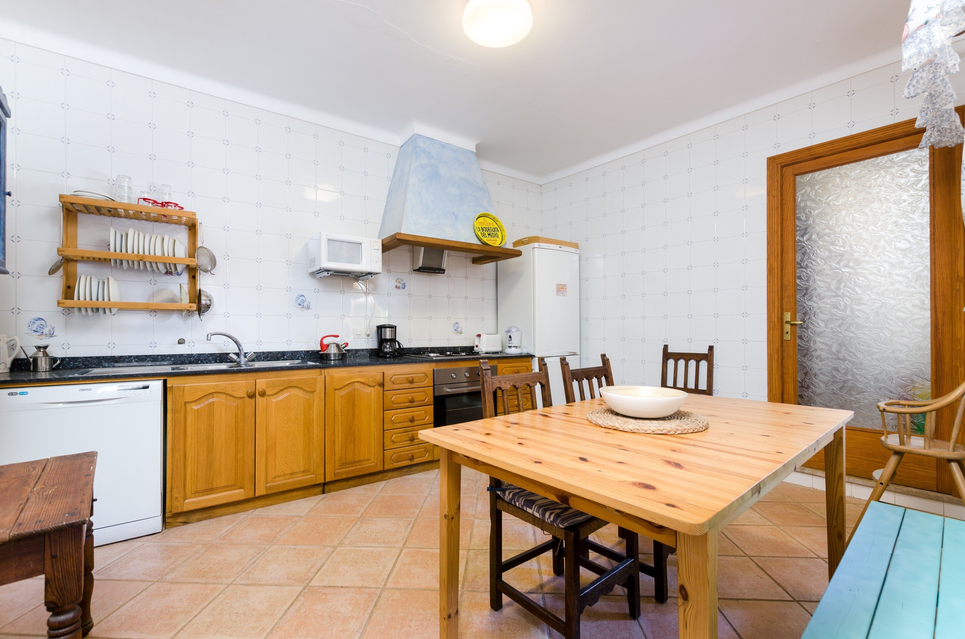 Una cocina con armarios de madera, una mesa de comedor de madera y un lavamanos.