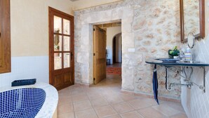 A bathroom with a bathtub, a sink, and a mirror. There is a door leading to another room. - CAN MORA - Villa with private pool in Campos. Free WiFi (Campos)