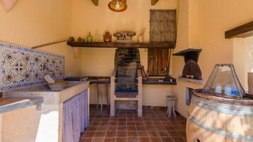 Una cocina rústica con horno de ladrillo, salpicadero de azulejos y estanterías de madera.