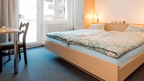 Quarto de hotel com cama, escrivaninha e cadeira.