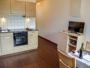 A modern kitchen with wooden cabinets, a built-in oven, and a dining area with a table set for two.