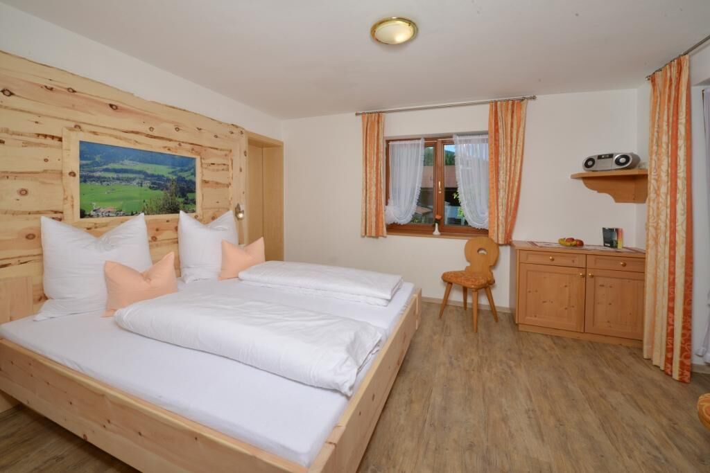 Een slaapkamer met twee bedden, een bureau, een stoel en een radio op een plank.
