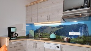 A kitchen with wooden cabinets, a microwave, a kettle, and a dishwasher. - (2) Ferienwohnung 35 qm mit Balkon (Reit im Winkl)