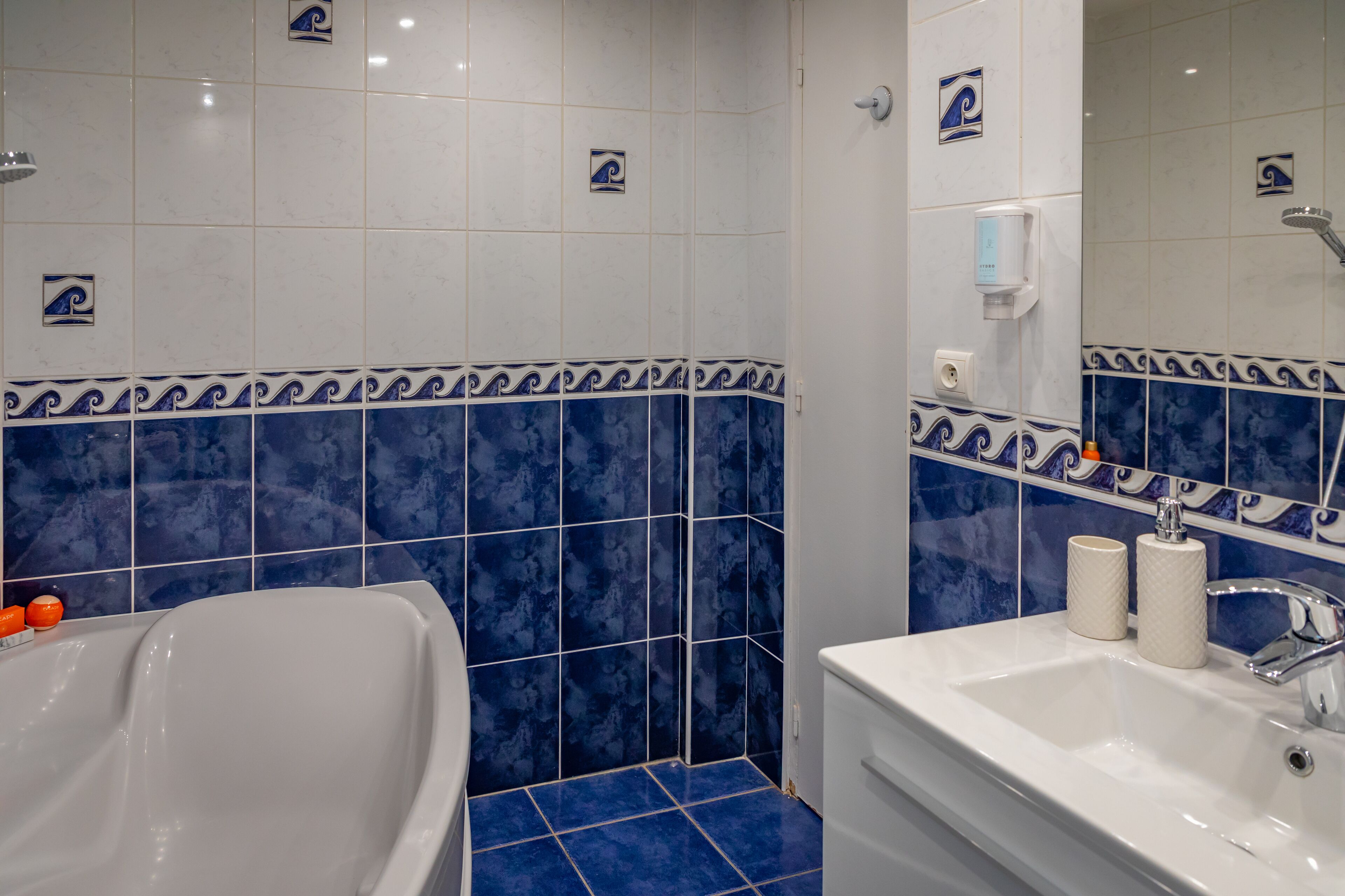 Ein Badezimmer mit Badewanne, Waschbecken und blauen Fliesen.