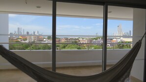 A balcony with a view of a cityscape, including buildings and greenery.