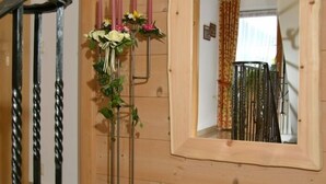 En interiör med träpanel, en spegel, en metallpall med blommor och en trappa.