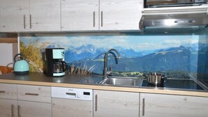 Ett kök med träskåp, en diskmaskin från Bosch, en kaffebryggare från Siemens, en mikrovågsugn från Bosch och en diskho i rostfritt stål.