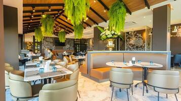 A modern restaurant interior with hanging greenery, marble flooring, and contemporary furniture.
