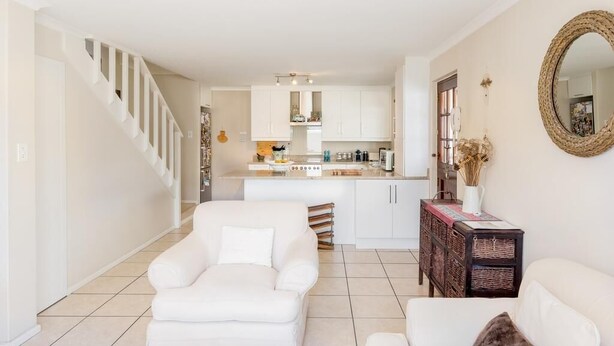 Una sala de estar moderna con una escalera, una cocina al fondo y un comedor.
