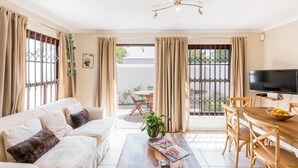 Una sala de estar con sofá, mesa de centro, televisor y comedor.
