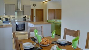 A modern kitchen with a dining area, wooden furniture, and a green sofa. - Woodland Lodge - UK6651 (Hundred House, near Builth Wells)