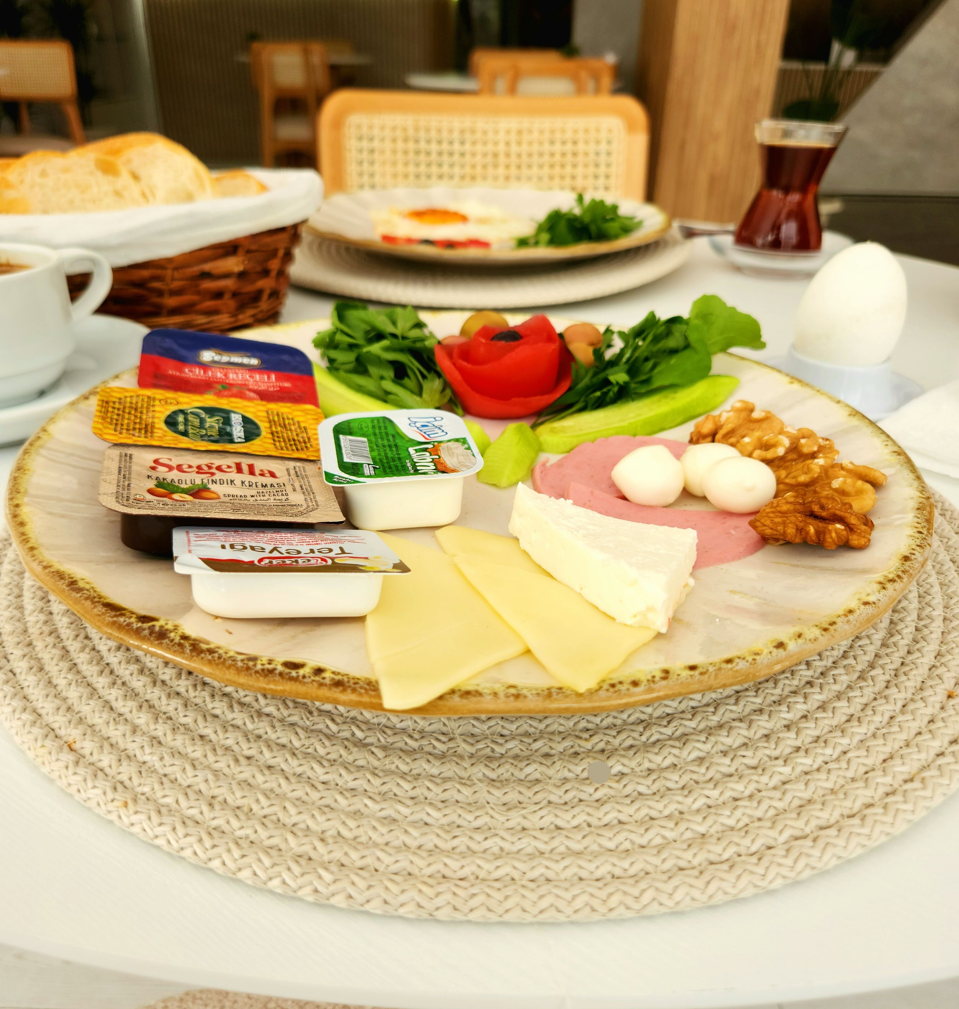 A breakfast setting with a variety of cheeses, nuts, and fresh vegetables on a round plate.