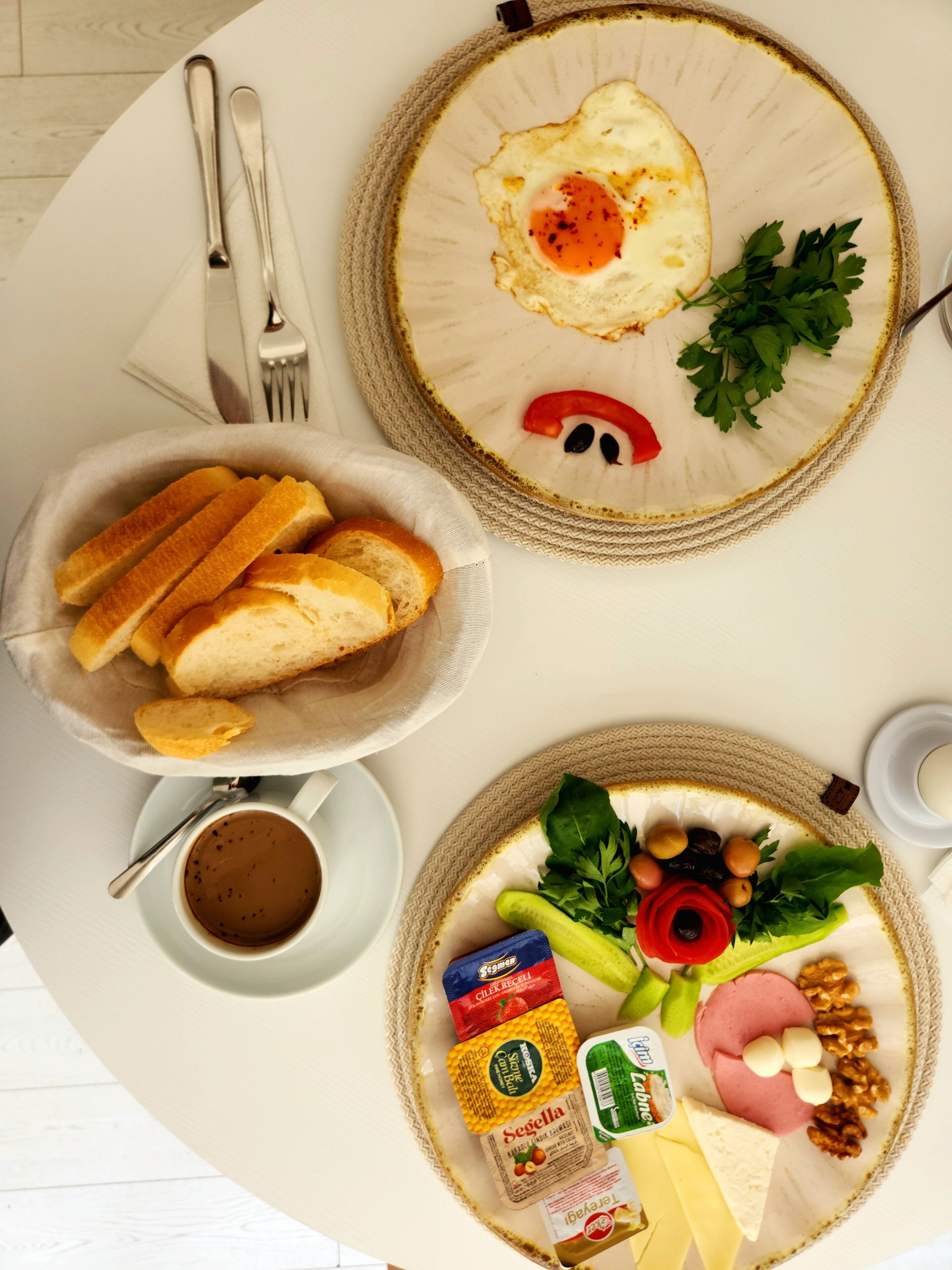 A breakfast table with bread, eggs, cheese, ham, and various condiments.