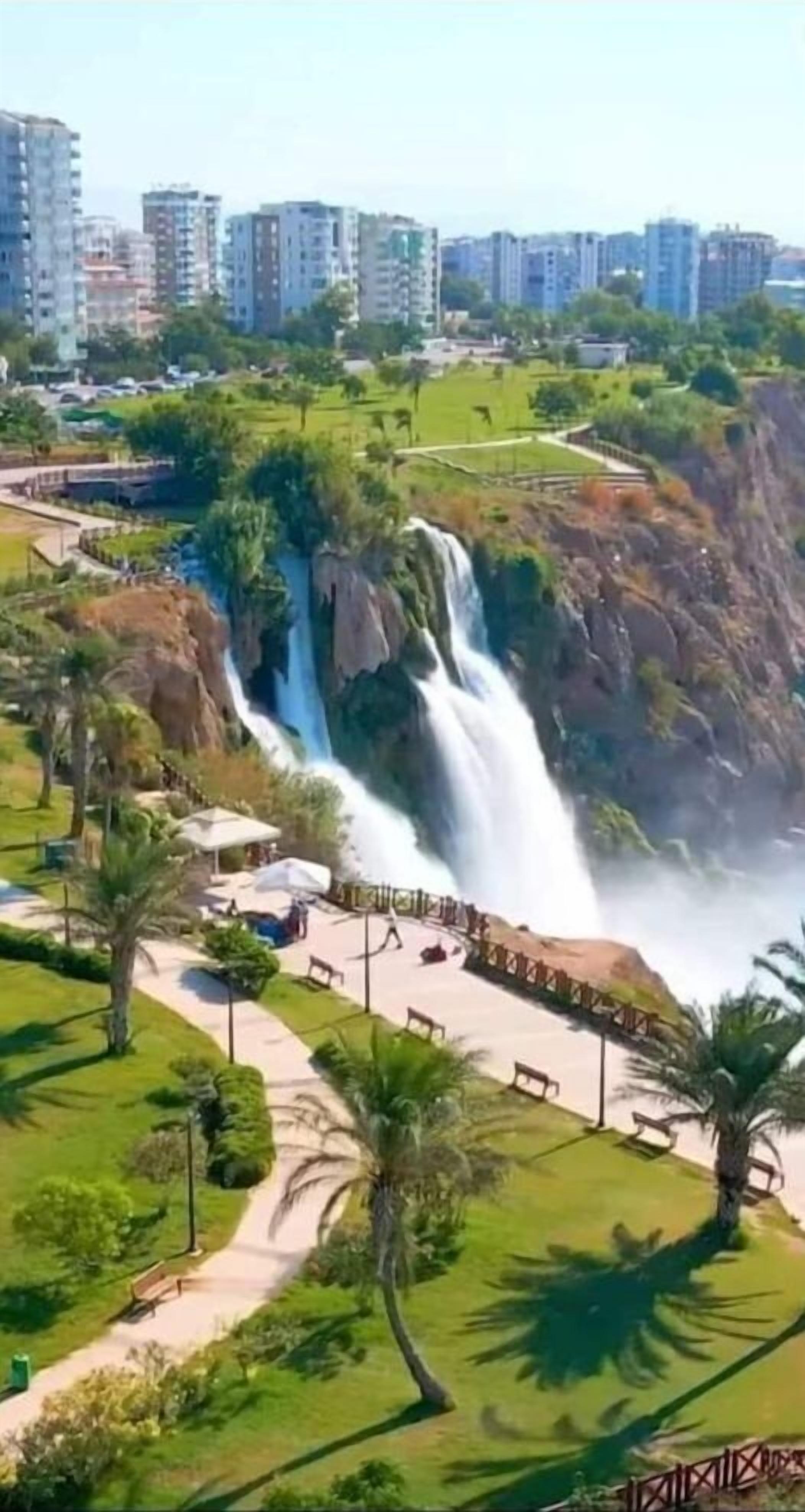 Una cascada en un parque con senderos y bancos.