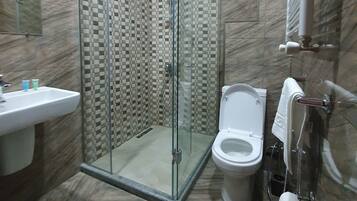 A bathroom with a glass-enclosed shower, a sink, a toilet, and a towel rack.