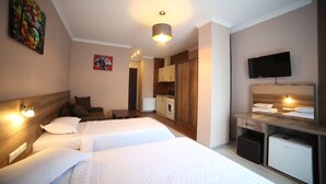 A hotel room with two beds, a TV, a washing machine, and a small kitchenette. - Hotel Soft (Batumi)
