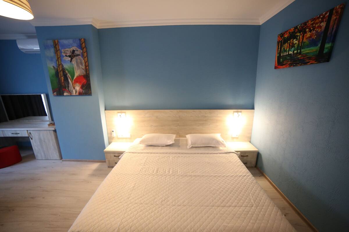 A bedroom with a bed, two bedside tables, a desk, and a chair.