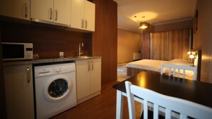 A compact hotel room with a washing machine, a small kitchenette, a bed, and a dining area. - Hotel Soft (Batumi)