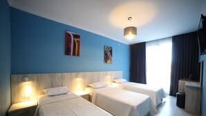 A hotel room with three beds, a wooden headboard, a flat-screen TV, and artwork on the walls. - Hotel Soft (Batumi)