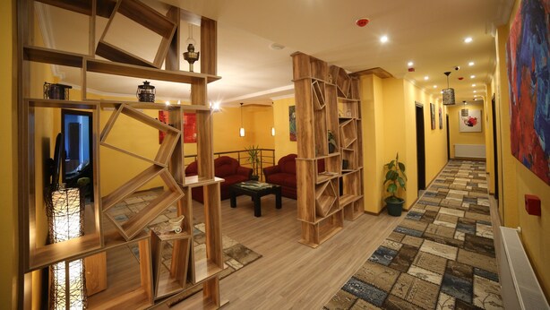 A hallway with wooden shelves, a sofa, and a patterned rug. - Hotel Soft (Batumi)