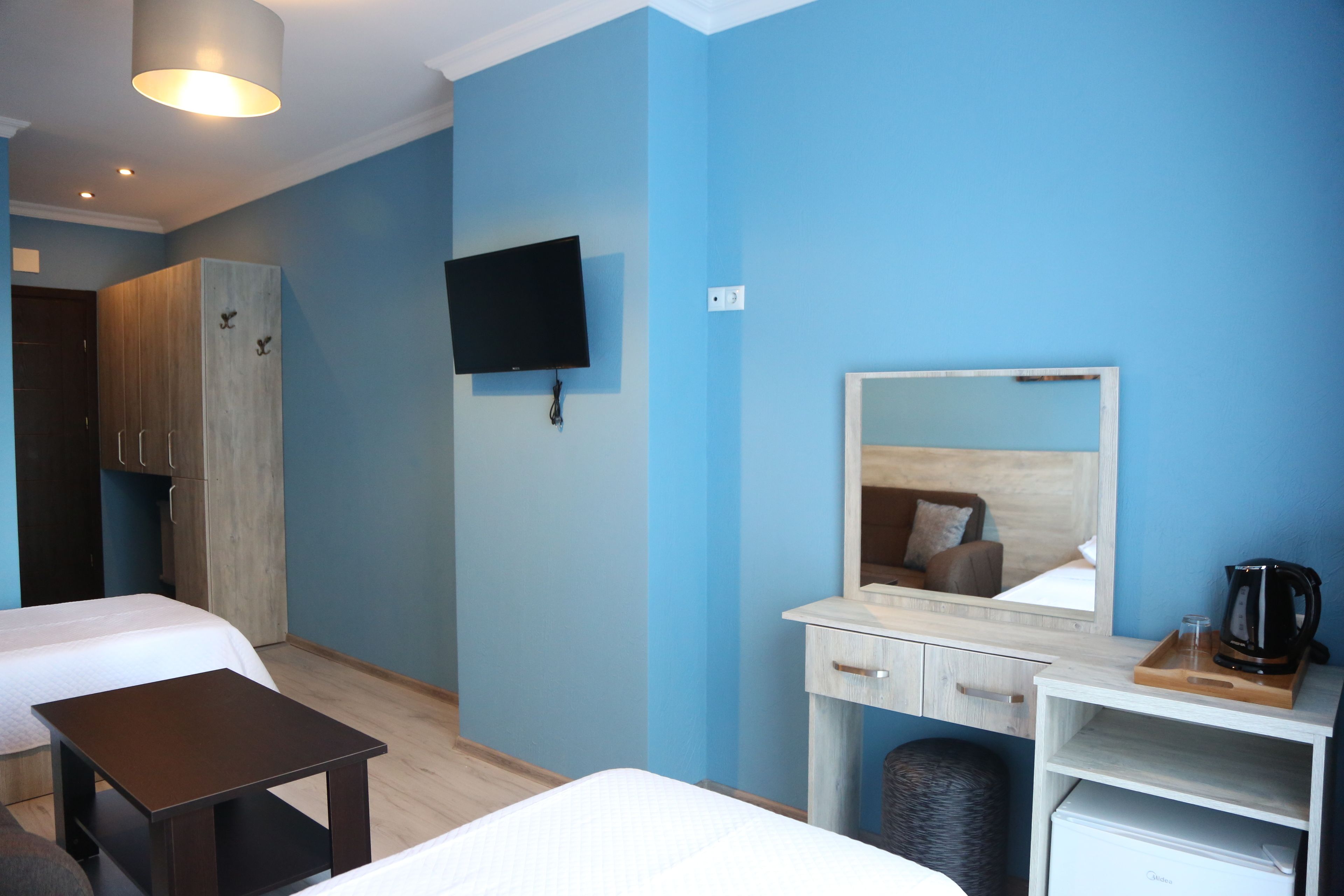 Una habitación de hotel con cama, escritorio con espejo, televisor y armario.