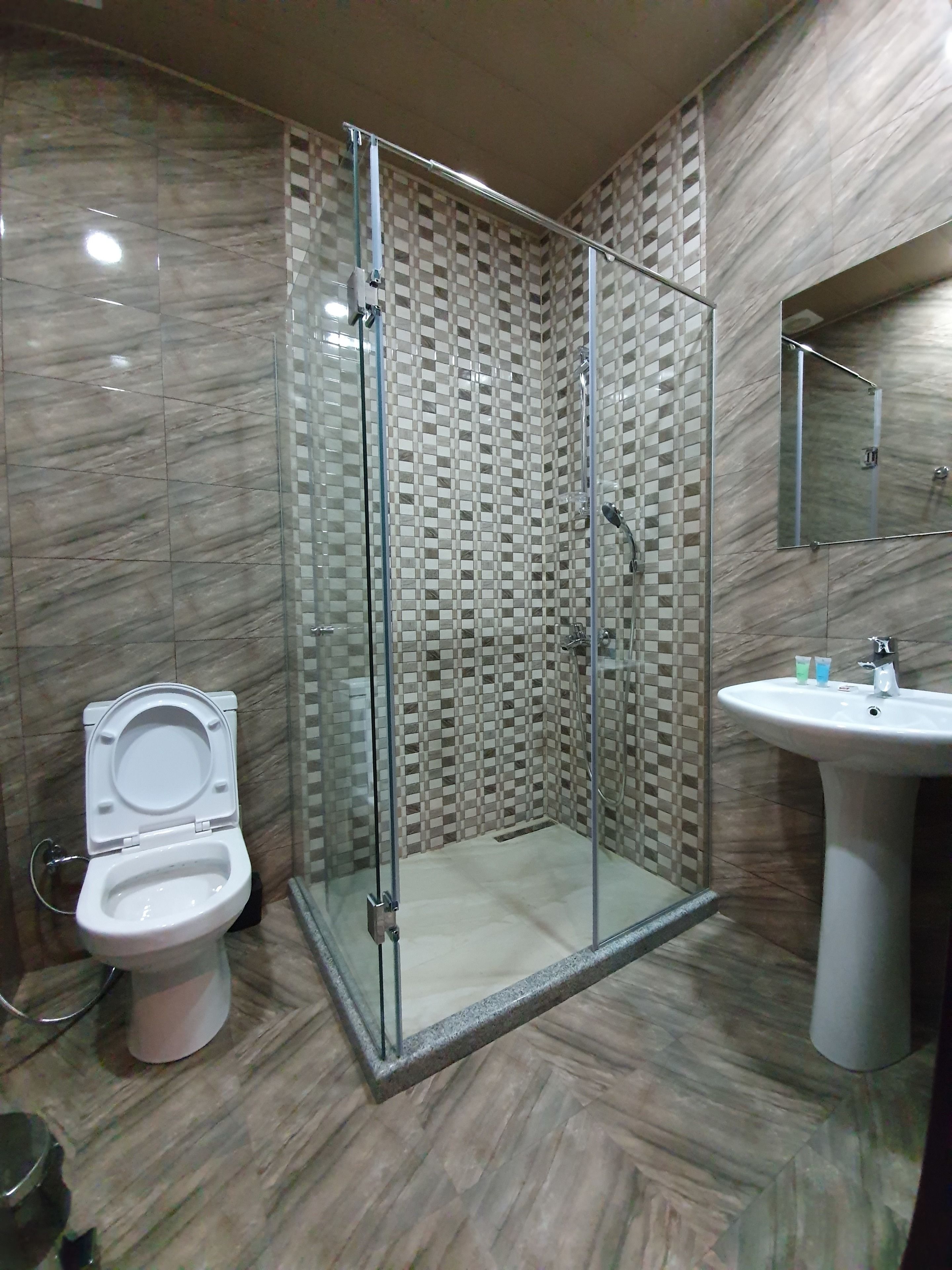 A bathroom with a glass-enclosed shower, a toilet, and a sink.