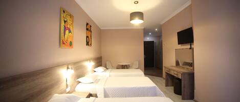 A hotel room with two beds, a desk, a chair, a television, and artwork on the wall.