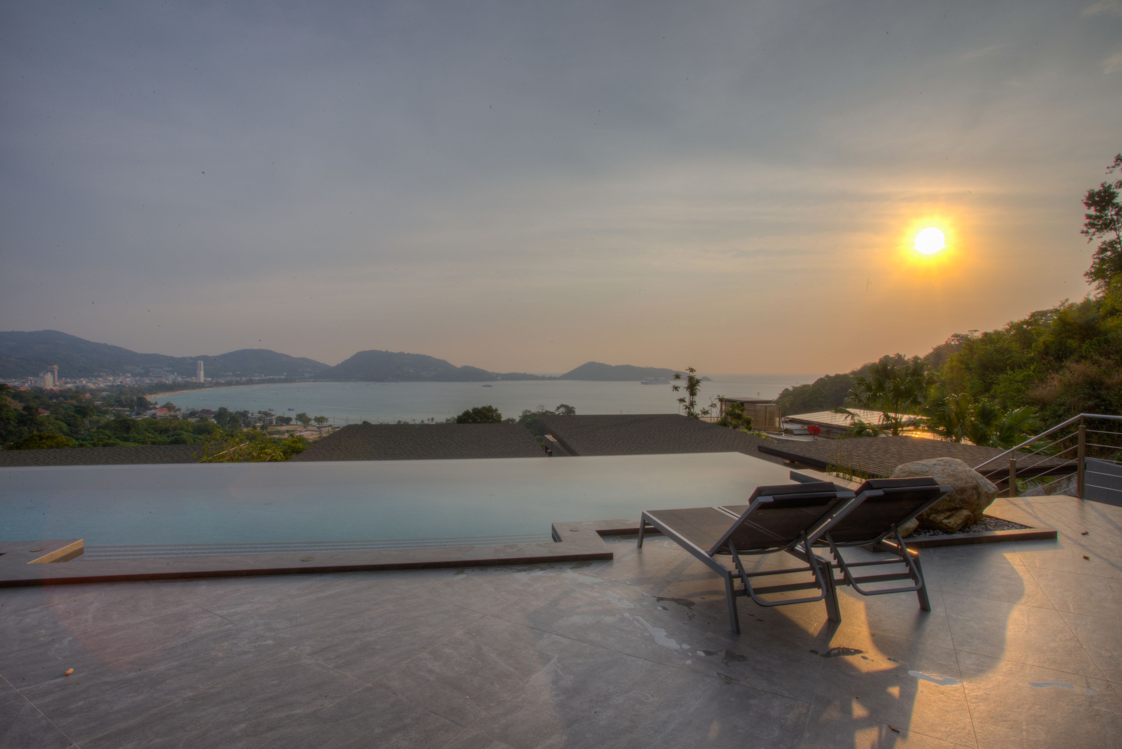 A poolside area with lounge chairs and a view of the sea.
